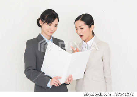 兩個穿西裝的女人一邊看材料一邊開會 兩個穿西裝的女人一邊看材料一邊開會 87541872