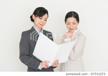 Two women in suits having a meeting while looking at the materials Two women in suits having a meeting while looking at the materials 87541873