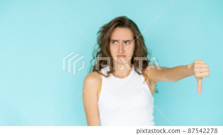 Dislike gesture. Displeased woman. Bad solution. Dissatisfied defocused pretty lady showing thumb down expressing false choice isolated blue. 87542278