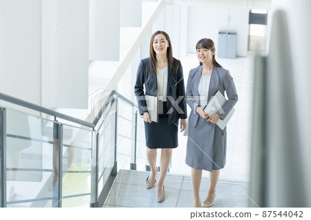 爬上商務辦公室樓梯的兩名女商人 87544042