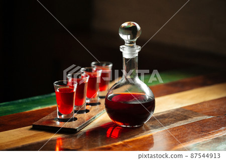 Decanter with red berry liqueur and shot glasses Decanter with red berry liqueur and shot glasses 87544913