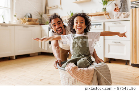 Happy father playing with son while washing in the home laundryin kitchen 87545186