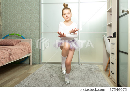 A little ballerina in a white swimsuit dances at home, learns to dance remotely. Dance lessons at home A little ballerina in a white swimsuit dances at home, learns to dance remotely. Dance lessons at home 87546073