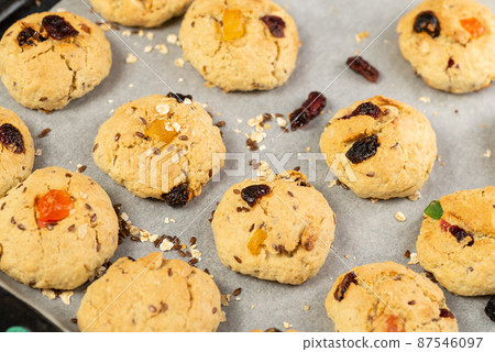 Refrigeration of freshly baked soft oatmeal cookies with raisins, candied fruits, flax and sesame seeds and walnuts on baking paper 87546097
