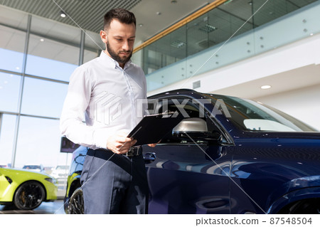 the seller at the car dealership prepares documents for the buyer of the car 87548504