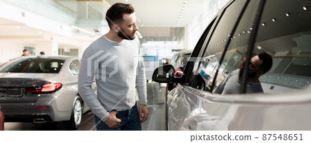 young man chooses a new car in a premium car dealership 87548651