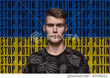 Portrait of young man asking to stop Putin isolated over blue and yellow flag background with lettering 87549223