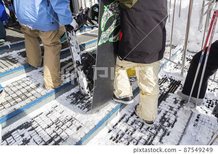 At the feet of people lining up in a gondola at a ski resort At the feet of people lining up in a gondola at a ski resort 87549249