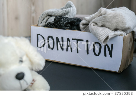Donation box with old used toys and clothes indoors. Happy Charity. Box with clothes in it. close-up. Clothing donation. Winter clothes in a cardboard box. Donation box with old used toys and clothes indoors. Happy Charity. Box with clothes in it. close-up. Clothing donation. Winter clothes in a cardboard box. 87550398