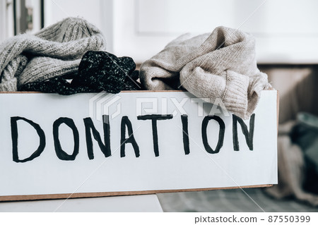 Donation box with old used clothes indoors. Happy Charity. Winter clothes in a cardboard box. Clothing donation or recycling Donation box with old used clothes indoors. Happy Charity. Winter clothes in a cardboard box. Clothing donation or recycling 87550399