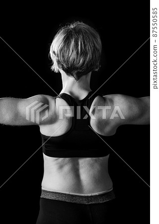 Low key studio portrait of a 35 year old white woman, turning her shaped back 87550585