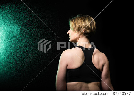 Low key studio portrait of a 35 year old white woman turning her back with drops of water 87550587