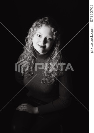 Studio Portrait of a 21 year old white blonde woman with curling hair Studio Portrait of a 21 year old white blonde woman with curling hair 87550702