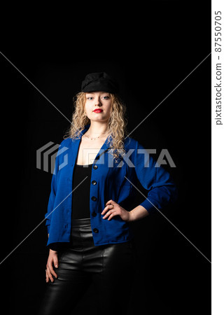 Studio portrait of a 21 year old white blonde woman with curling hair wearing a hat, hand on hips Studio portrait of a 21 year old white blonde woman with curling hair wearing a hat, hand on hips 87550705