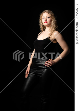 Fashion studio Portrait of a 21 year old white blonde woman with curling hair wearing a black tank top Fashion studio Portrait of a 21 year old white blonde woman with curling hair wearing a black tank top 87550707