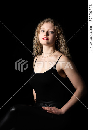 Fashion studio Portrait of a 21 year old white blonde woman with curling hair wearing a black tank top Fashion studio Portrait of a 21 year old white blonde woman with curling hair wearing a black tank top 87550708