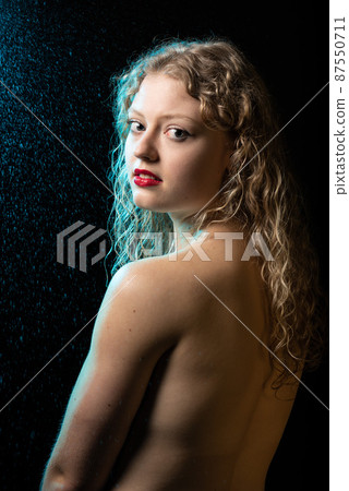 Sensual studio Portrait of a 21 year old white blonde woman with curling hair with a naked back Sensual studio Portrait of a 21 year old white blonde woman with curling hair with a naked back 87550711