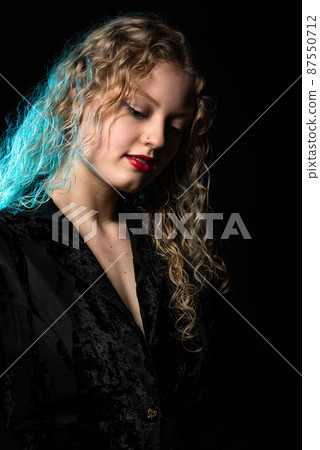 Glamour studio Portrait of a 21 year old white blonde woman with curling hair 87550712