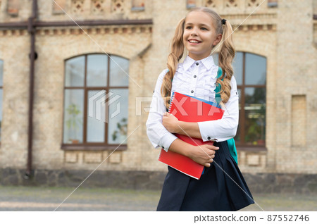 Happy school child in uniform back-to-school carrying books and backpack, copy space Happy school child in uniform back-to-school carrying books and backpack, copy space 87552746