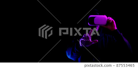 Vr goggles virtual reality. Young man in digital helmet for 3d virtual reality game isolated on black neon background. Study and virtual world in 3D simulation. Vr goggles virtual reality. Young man in digital helmet for 3d virtual reality game isolated on black neon background. Study and virtual world in 3D simulation. 87553465