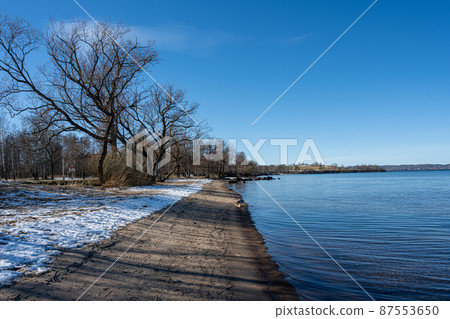 A lake winter beach covered with snow and a blue sky in the background 87553650