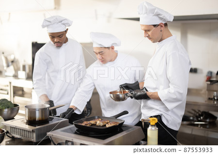 Chef cooks tasting sauce with a spoon while cooking in the kitchen 87553933