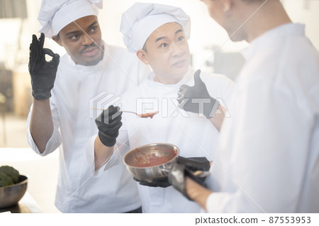 Chef cooks tasting sauce with a spoon while cooking in the kitchen Chef cooks tasting sauce with a spoon while cooking in the kitchen 87553953