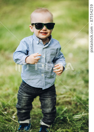 Portrait of stylish little boy posing in park in 87554259