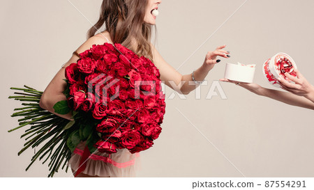 Beautiful lady with red roses taking a sweet from 87554291