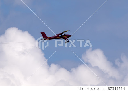 Red small sport plane flying in the sky pulls on a rope the glider plane Red small sport plane flying in the sky pulls on a rope the glider plane 87554514