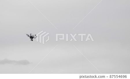 Flying helicopter dron on a background of white clouds 87554696