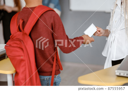 Boy passing paper note to girl at school Boy passing paper note to girl at school 87555957