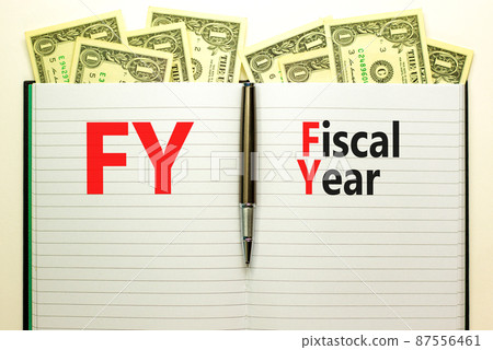 FY Fiscal year symbol. Concept words FY Fiscal year on white note. Metallic pen. Dollar bills. Beautiful white background. Business and FY fiscal year concept. 87556461
