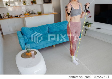 Sporty woman doing exercise with fitness rope at home 87557321