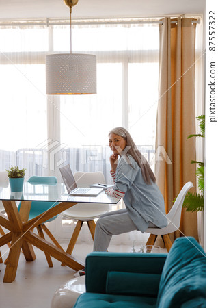 Woman sitting at the table with laptop in living room 87557322