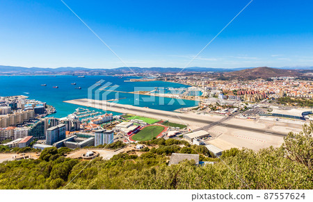Border between Gibraltar and Spain with runway in the middle, La Linea town in the backgound 87557624