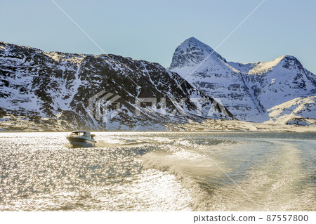 Motor boat in the middle of Nuuk fjord with frozen rocks in the background, Greenland Motor boat in the middle of Nuuk fjord with frozen rocks in the background, Greenland 87557800