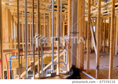 Unfinished of new building the installed featuring hot and cold water PEX plastic plumbing tubes in laundry room 87559118