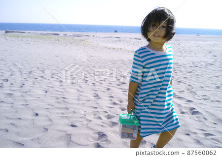 一個女孩在沙灘上撿貝殼 87560062