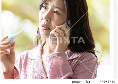一個穿著睡衣的女人,看著溫度計的溫度測量結果,打電話給某處 一個穿著睡衣的女人,看著溫度計的溫度測量結果,打電話給某處 87561249