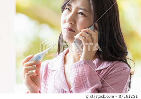 一個穿著睡衣的女人,看著溫度計的溫度測量結果,打電話給某處 一個穿著睡衣的女人,看著溫度計的溫度測量結果,打電話給某處 87561251