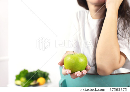 Close-up of a woman's hand holding an apple. The concept of spring and vitamins. Detox food. Front view. Close-up of a woman's hand holding an apple. The concept of spring and vitamins. Detox food. Front view. 87563875