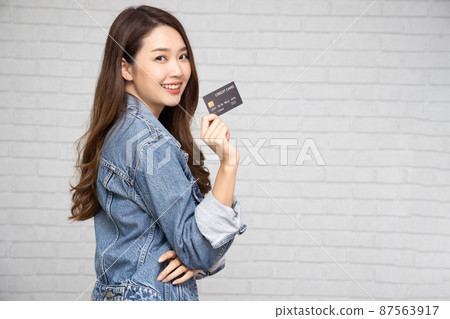 Young beautiful Asian woman smiling, showing, presenting credit card for making payment or paying online business, Pay a merchant or as a cash advance for goods, Cardholder or A person who owns a card Young beautiful Asian woman smiling, showing, presenting credit card for making payment or paying online business, Pay a merchant or as a cash advance for goods, Cardholder or A person who owns a card 87563917