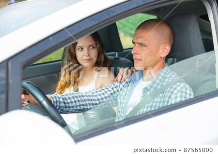 Focused man driving car with girl in passenger seat Focused man driving car with girl in passenger seat 87565000