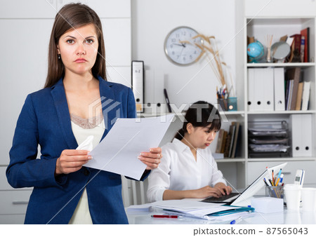 Business woman crying standing in office with working colleague behind 87565043