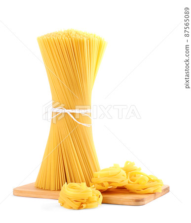 Wooden board with spaghetti and tagliatelle pasta isolated on white Wooden board with spaghetti and tagliatelle pasta isolated on white 87565089