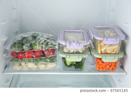 Plastic bags and containers with different frozen vegetables in refrigerator Plastic bags and containers with different frozen vegetables in refrigerator 87565185