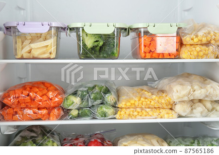 Plastic bags and containers with different frozen vegetables in refrigerator Plastic bags and containers with different frozen vegetables in refrigerator 87565186