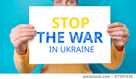 Young woman cover half face banner with Stop the war in Ukraine inscription isolated over blue color background 87565436