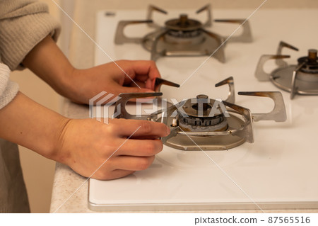 A woman cleaning the stove cleaning 87565516